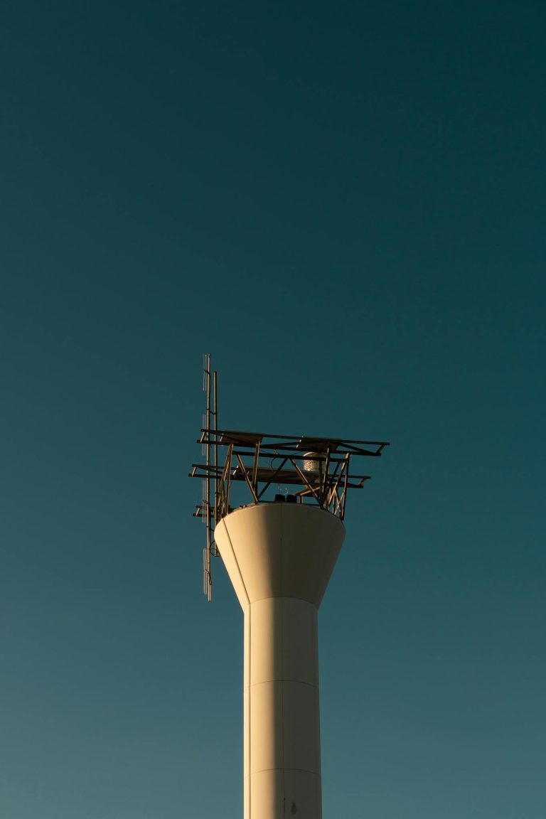A sleek communication tower designed for industrial usage, silhouetted against a clear sky.