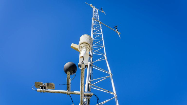 Close-up view of a communication tower with antennas under a clear blue sky, showcasing modern technology.